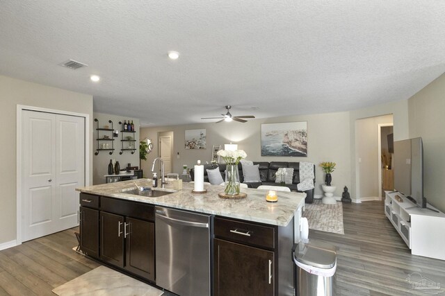 kitchen with sink, hardwood / wood-style flooring, stainless steel dishwasher, ceiling fan, and a center island with sink