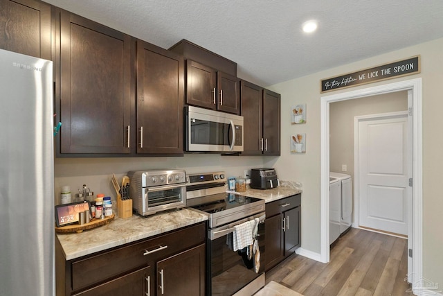 kitchen featuring dark brown cabinetry, separate washer and dryer, wood-type flooring, a textured ceiling, and stainless steel appliances