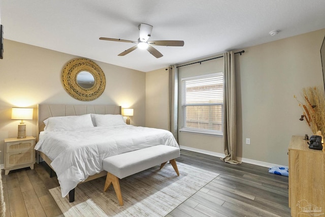 bedroom with dark wood-type flooring, a ceiling fan, and baseboards