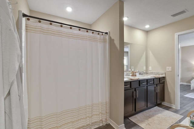 full bathroom with visible vents, vanity, baseboards, and wood finished floors