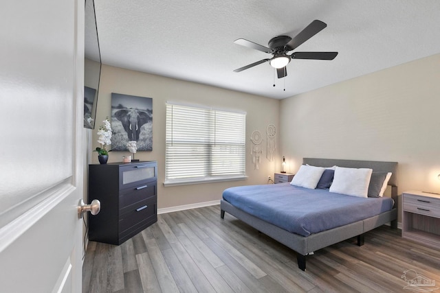 bedroom featuring hardwood / wood-style flooring, a textured ceiling, and ceiling fan