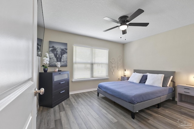 bedroom featuring a ceiling fan, a textured ceiling, baseboards, and dark wood-type flooring