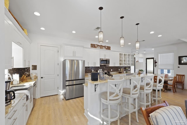 kitchen featuring stainless steel appliances, white cabinetry, light wood-style floors, visible vents, and a center island