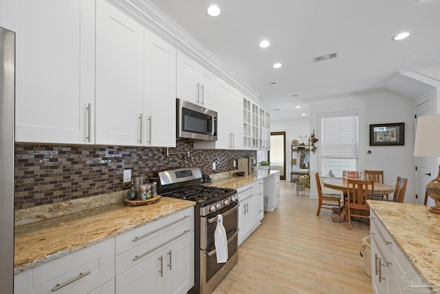 kitchen featuring white cabinetry, visible vents, light wood-style floors, appliances with stainless steel finishes, and backsplash