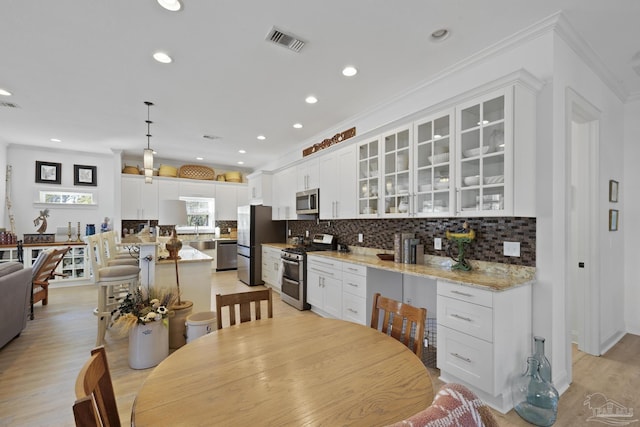 kitchen with stainless steel appliances, light wood-type flooring, glass insert cabinets, and decorative backsplash