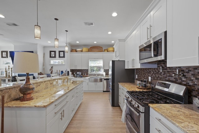 kitchen featuring stainless steel appliances, tasteful backsplash, a sink, and white cabinetry