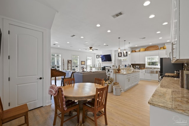 dining area with a fireplace, recessed lighting, visible vents, light wood-style flooring, and ceiling fan