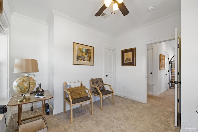 living area featuring baseboards, ornamental molding, a ceiling fan, and light colored carpet