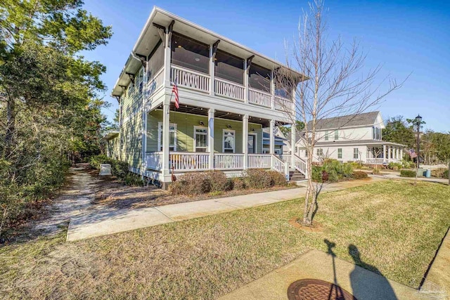 view of front of house featuring covered porch, a front lawn, and a sunroom