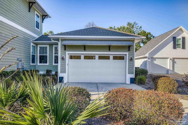 view of home's exterior with a shingled roof, driveway, and a garage