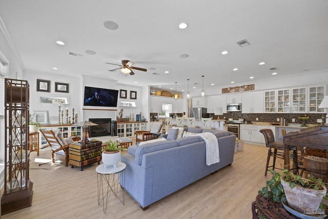 living area featuring light wood-style floors, visible vents, and a fireplace with raised hearth