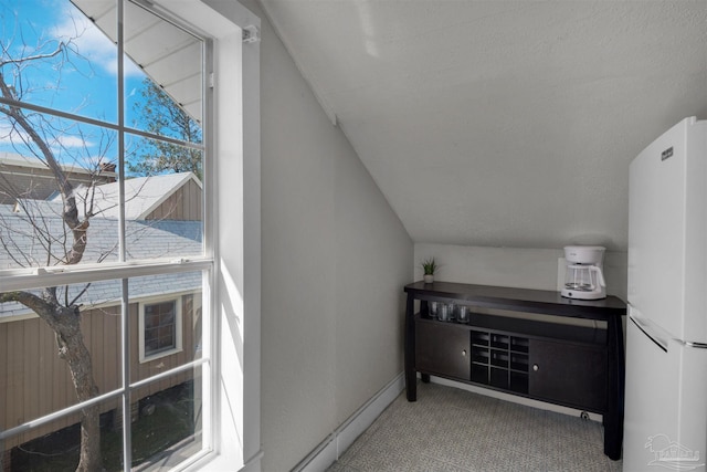 interior space with a textured ceiling, carpet, and vaulted ceiling