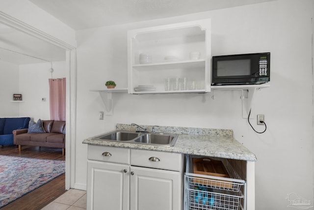 bar featuring white cabinetry, sink, and light hardwood / wood-style flooring