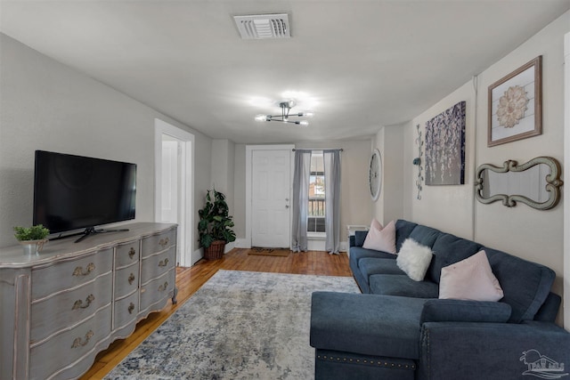 living room with light hardwood / wood-style floors and an inviting chandelier