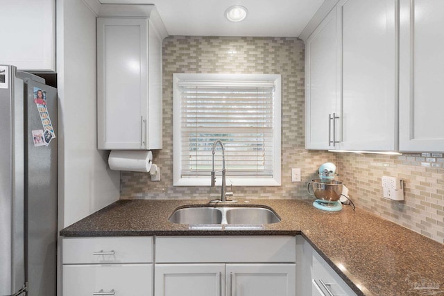 kitchen featuring sink, stainless steel refrigerator, and white cabinets