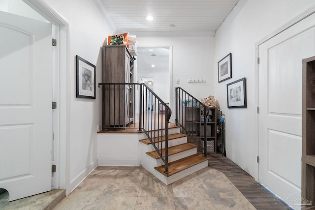 staircase featuring wood-type flooring and ornamental molding