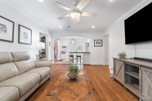 living room with hardwood / wood-style floors, ceiling fan, and crown molding