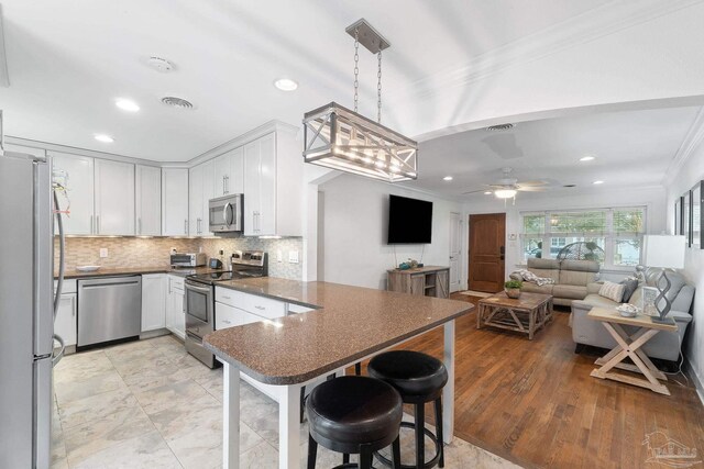 kitchen featuring appliances with stainless steel finishes, ceiling fan, decorative light fixtures, light hardwood / wood-style flooring, and white cabinets