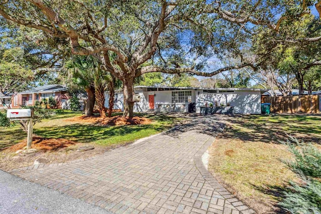 ranch-style home with a front lawn and fence