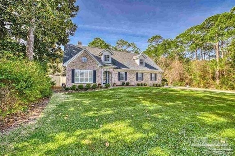 cape cod-style house featuring a front yard and a chimney