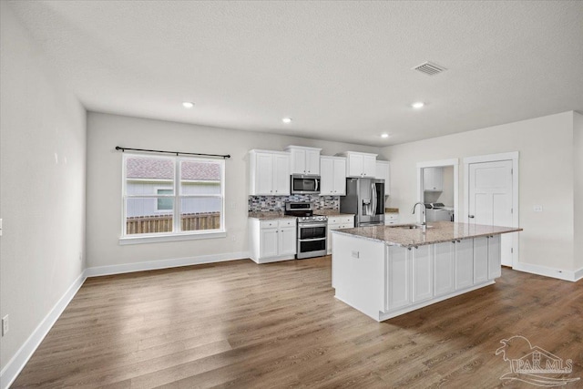 10826 Blacktail Loop, Pensacola, FL 32526 - kitchen featuring appliances with stainless steel finishes, white cabinets, an island with sink, dark wood-style floors, and a sink
