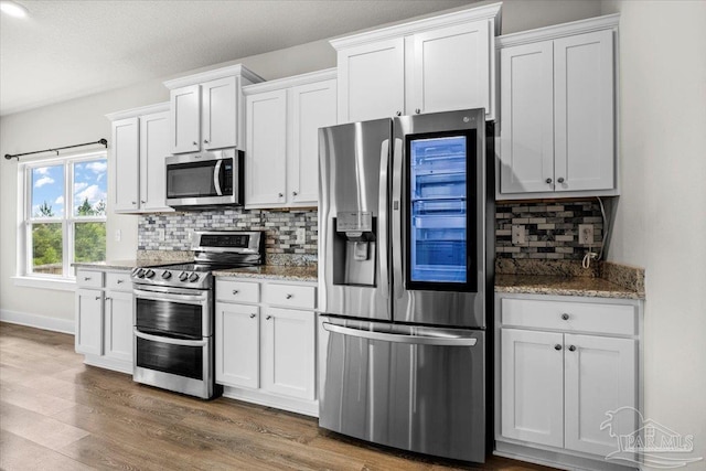 10826 Blacktail Loop, Pensacola, FL 32526 - kitchen with appliances with stainless steel finishes, decorative backsplash, white cabinets, dark wood-style floors, and light stone countertops