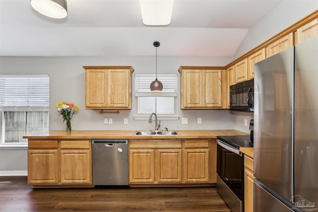 kitchen with a sink, dark wood-type flooring, vaulted ceiling, and stainless steel appliances
