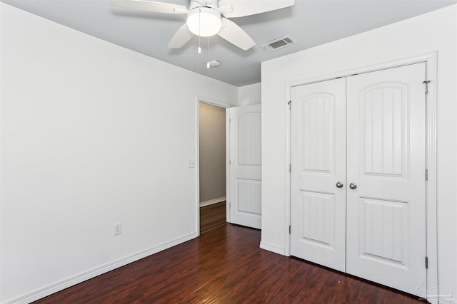 unfurnished bedroom with ceiling fan, dark wood finished floors, a closet, visible vents, and baseboards