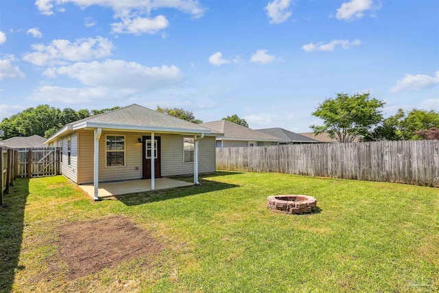 back of house featuring a fire pit, a patio area, a fenced backyard, a yard, and a shingled roof