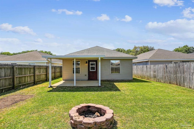 rear view of property with a yard, an outdoor fire pit, a fenced backyard, a patio, and roof with shingles