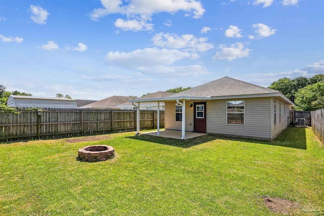back of property with a fenced backyard, a lawn, an outdoor fire pit, a patio, and a shingled roof
