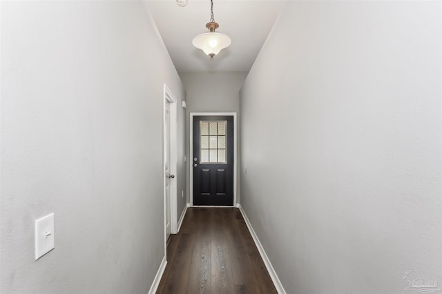 doorway with dark wood-style flooring and baseboards