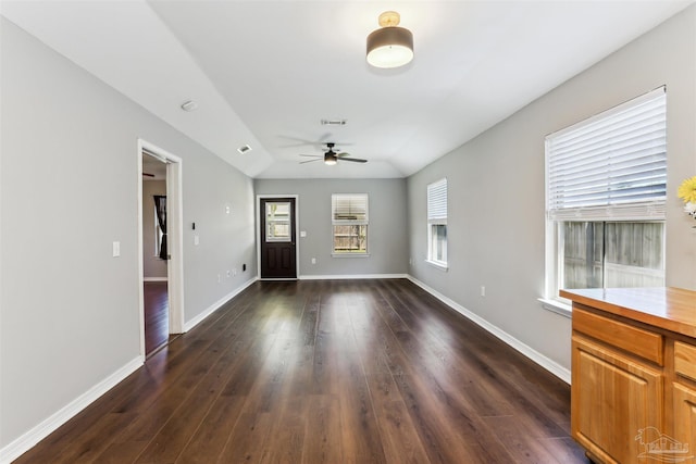 unfurnished living room with ceiling fan, baseboards, and dark wood-style floors
