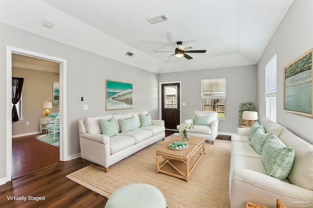living area with visible vents, a ceiling fan, a raised ceiling, and wood finished floors