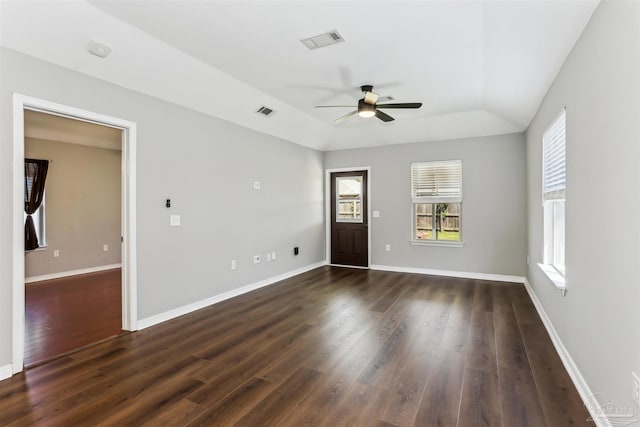 unfurnished room featuring a wealth of natural light, visible vents, a ceiling fan, and dark wood-style floors
