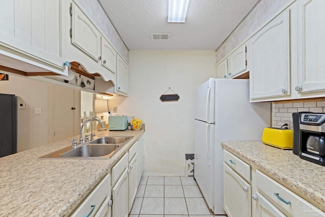 kitchen with white cabinets, tasteful backsplash, visible vents, and a sink