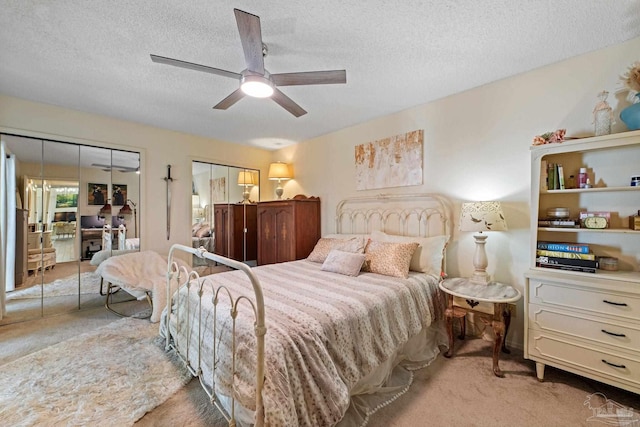 bedroom featuring a textured ceiling, a ceiling fan, two closets, and light carpet