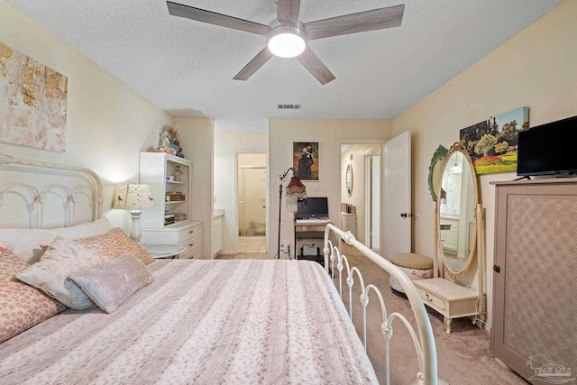 bedroom with visible vents, ceiling fan, a textured ceiling, light colored carpet, and connected bathroom