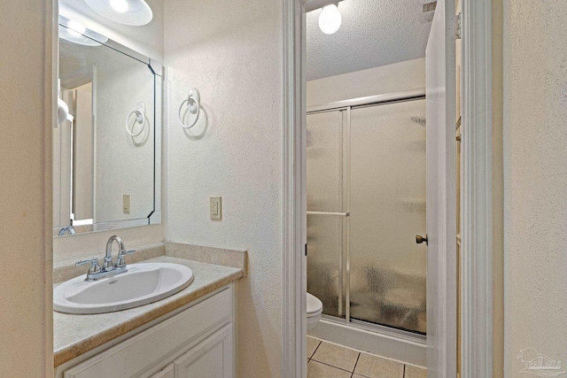 bathroom featuring toilet, a stall shower, a textured ceiling, tile patterned flooring, and vanity