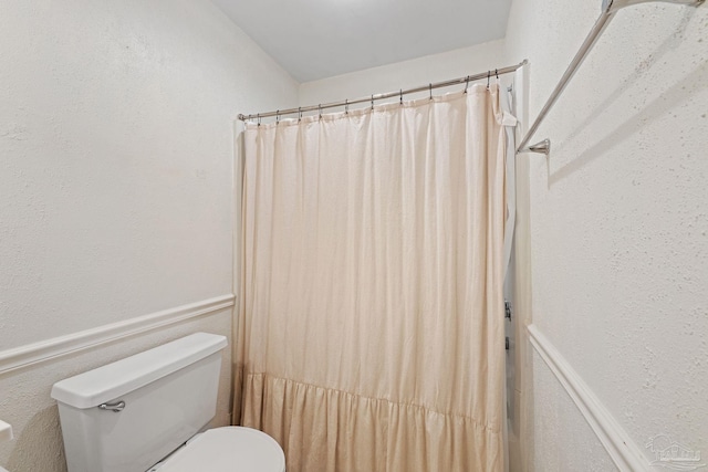 full bathroom with a wainscoted wall, curtained shower, and toilet