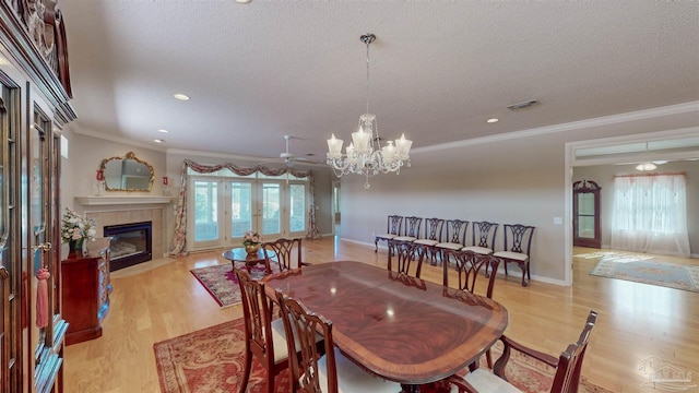 dining room with a fireplace, a wealth of natural light, light hardwood / wood-style flooring, and a textured ceiling