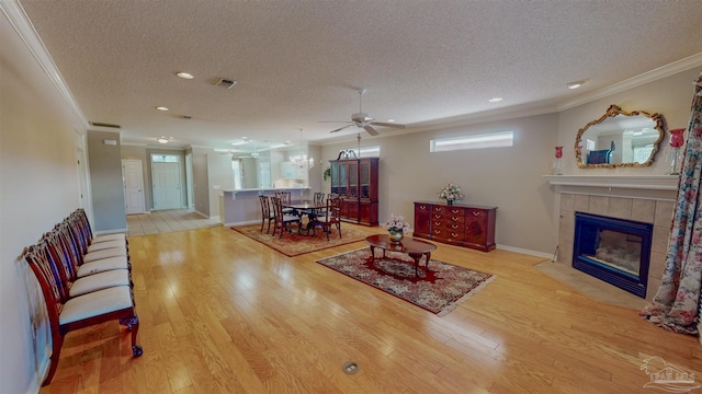 living room with ornamental molding, plenty of natural light, a fireplace, and light wood-type flooring