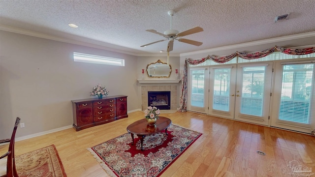 living room featuring a textured ceiling, ornamental molding, ceiling fan, a fireplace, and hardwood / wood-style floors