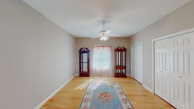 interior space featuring multiple closets, ceiling fan, hardwood / wood-style floors, and a textured ceiling