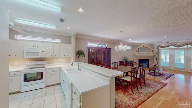 kitchen featuring sink, white appliances, ornamental molding, white cabinets, and decorative light fixtures