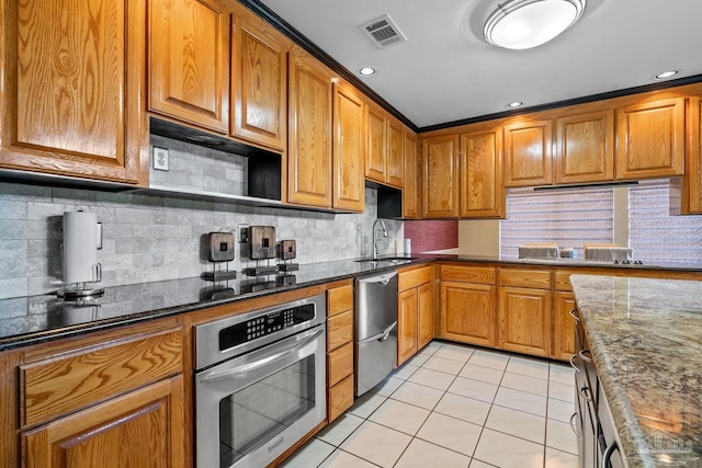 1567 Whisper Bay Blvd, Gulf Breeze, FL 32563 - kitchen with stainless steel appliances, a sink, light tile patterned flooring, brown cabinetry, and tasteful backsplash