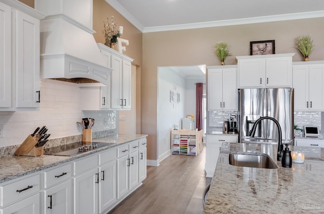 kitchen with ornamental molding, stainless steel refrigerator with ice dispenser, black electric stovetop, and white cabinets