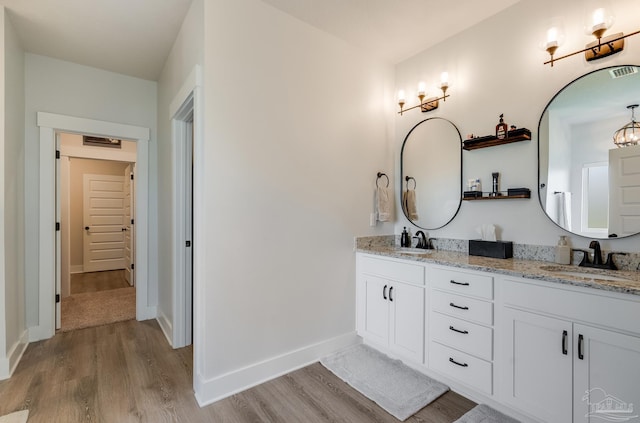bathroom with double vanity, a sink, and wood finished floors