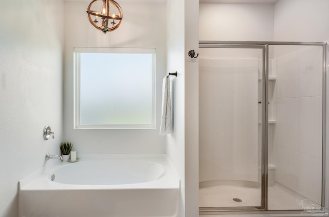 bathroom with a notable chandelier, a garden tub, and a stall shower
