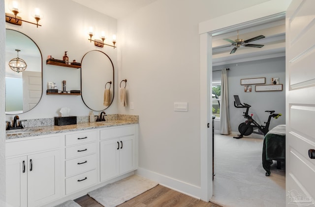 ensuite bathroom featuring baseboards, a sink, ceiling fan, and double vanity